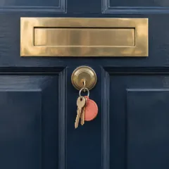 A navy front door with a set of keys in the lock